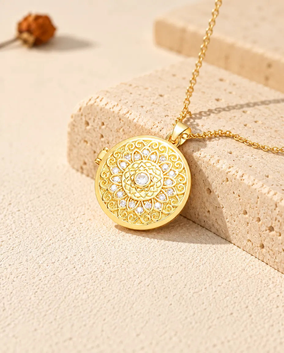 Collar relicario redondo dorado con flor mandala apoyado sobre un bloque de travertino