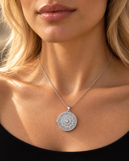 Mujer con jersey negro de punto que lleva el collar relicario redondo plateado con flor mandala