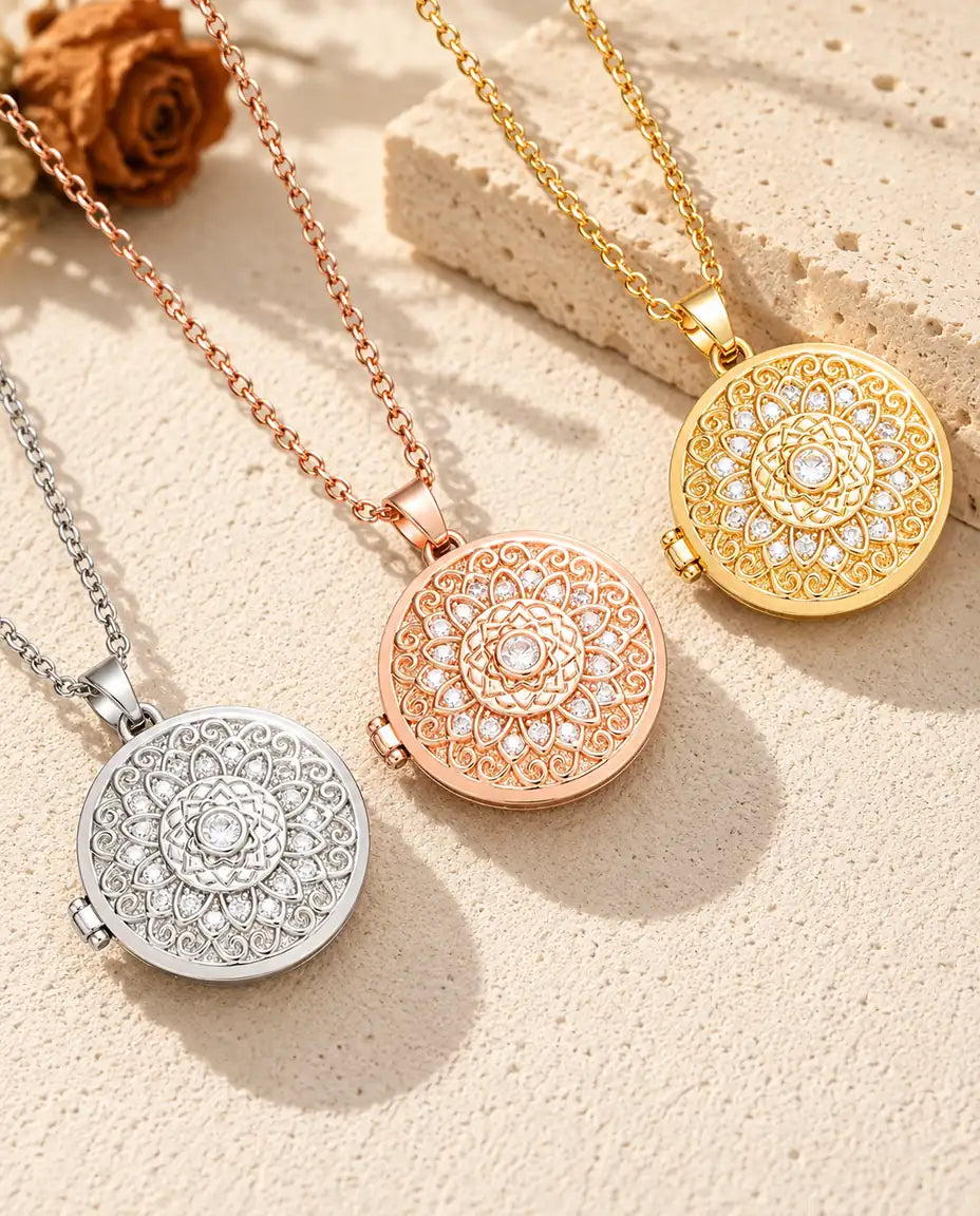 Tres relicarios con flor mandala, plateado, color oro rosa y dorado, colocados en diagonal sobre yeso crema