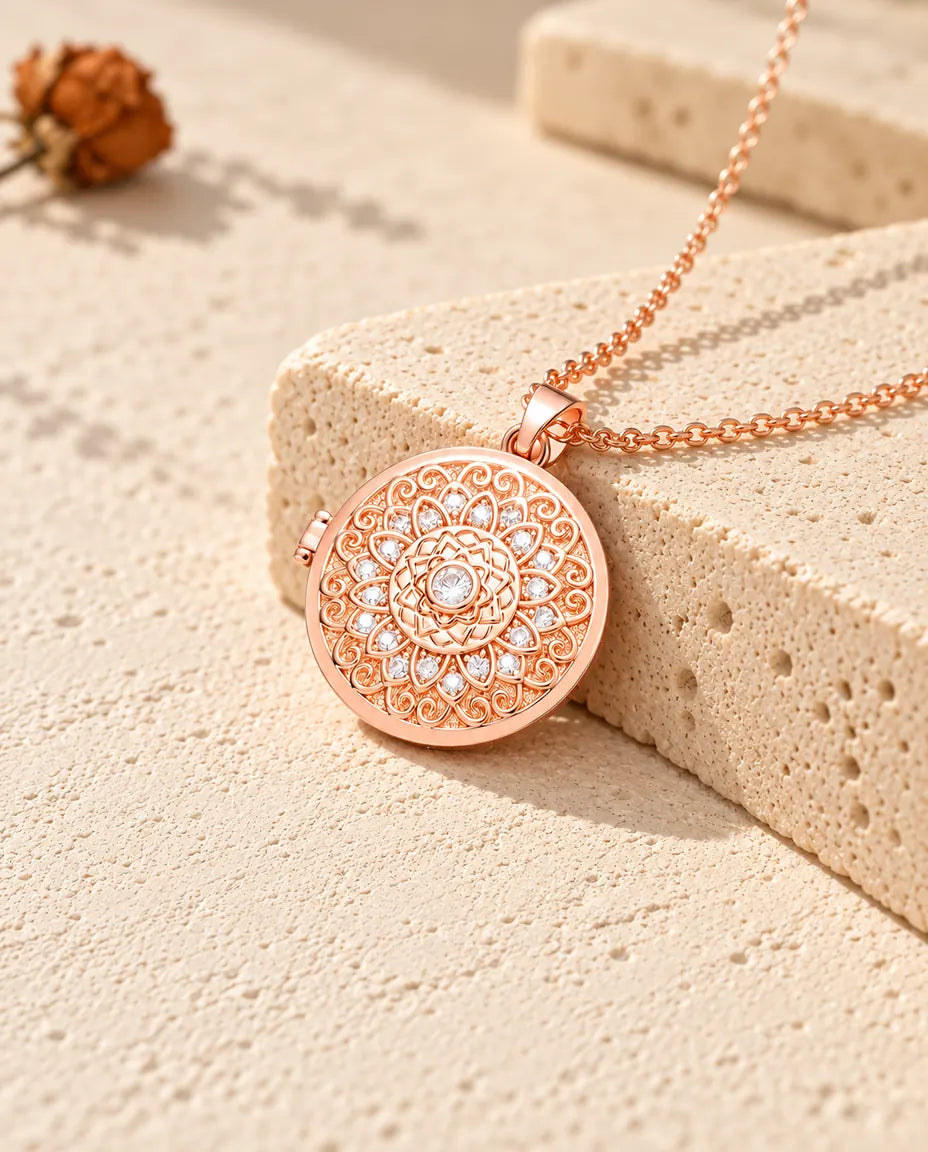 Collar relicario redondo color oro rosa con flor mandala sobre travertino con luz cálida de sol