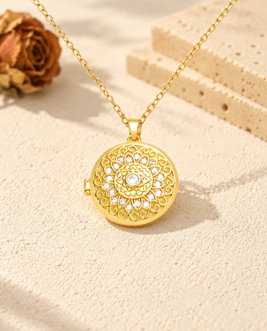 Vista frontal del relicario redondo dorado con la flor mandala, sus circonitas y la bisagra lateral