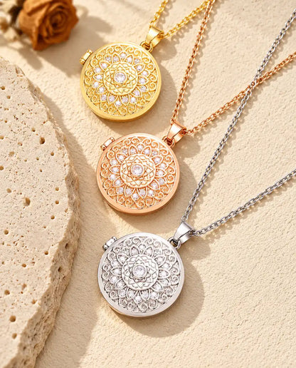 Relicarios redondos con flor mandala dorado, color oro rosa y plateado apilados junto a una losa de travertino