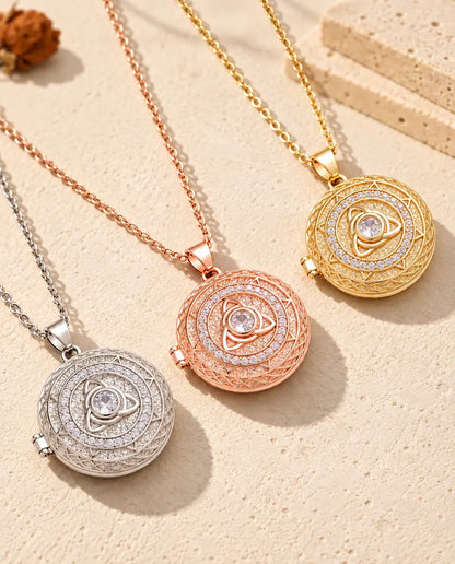 Tres relicarios con triqueta celta, plateado, color oro rosa y dorado, colocados en diagonal sobre yeso crema