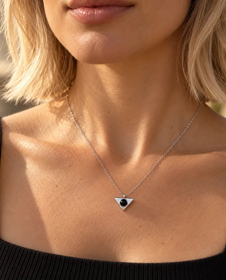 Mujer con un top negro que lleva el collar minimalista de triángulo plateado