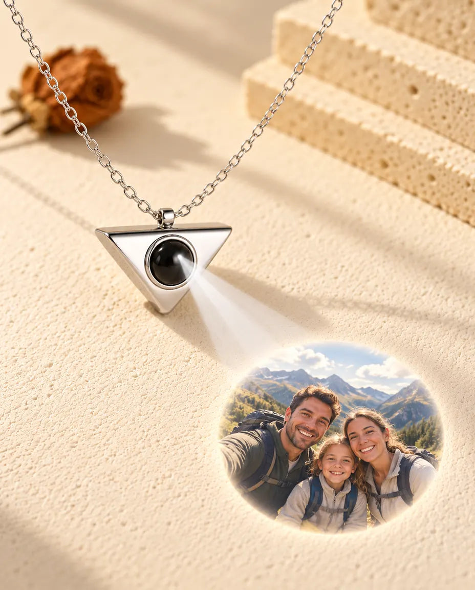 Collar de triángulo plateado que proyecta la foto de una familia de excursión sobre yeso crema