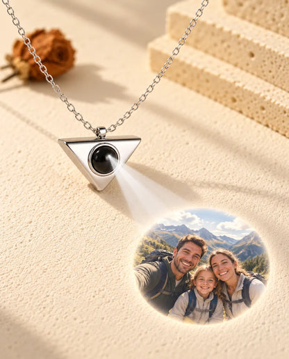 Collar de triángulo plateado que proyecta la foto de una familia de excursión sobre yeso crema