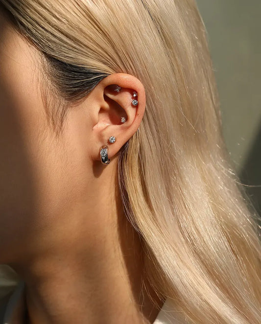 Pendientes de Moissanita Redonda con Arco Lateral en Plata 925 - llevado por una modelo, plano más amplio de oreja y cuello