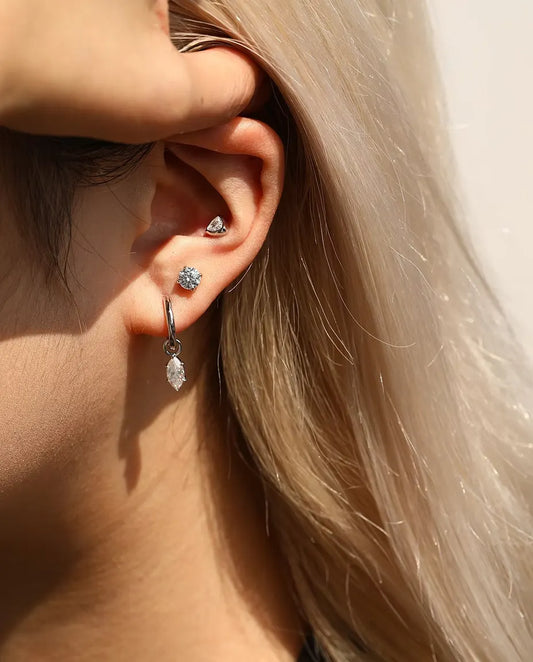 Pendientes Solitario de Moissanita de 5 mm con Cuatro Garras en Plata 925 - llevado por una modelo que se aparta el pelo tras la oreja