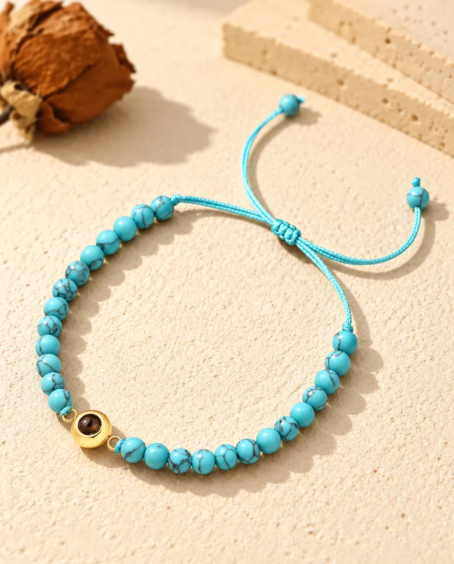 Pulsera de bolas con foto dentro personalizada: bolas azul jaspeado y aro dorado, sobre yeso color crema