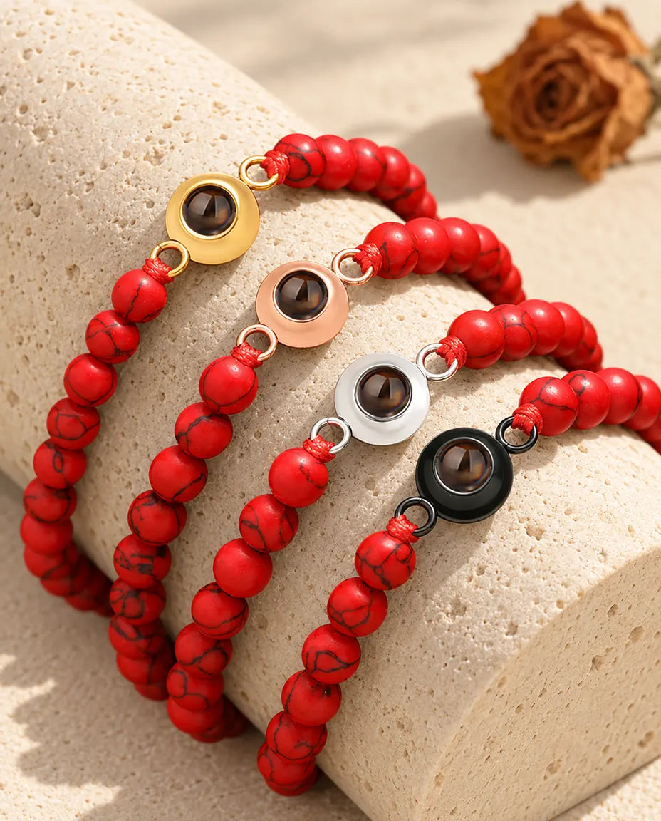 Pulseras de bolas rojo jaspeado en los cuatro colores de aro sobre un bloque de travertino