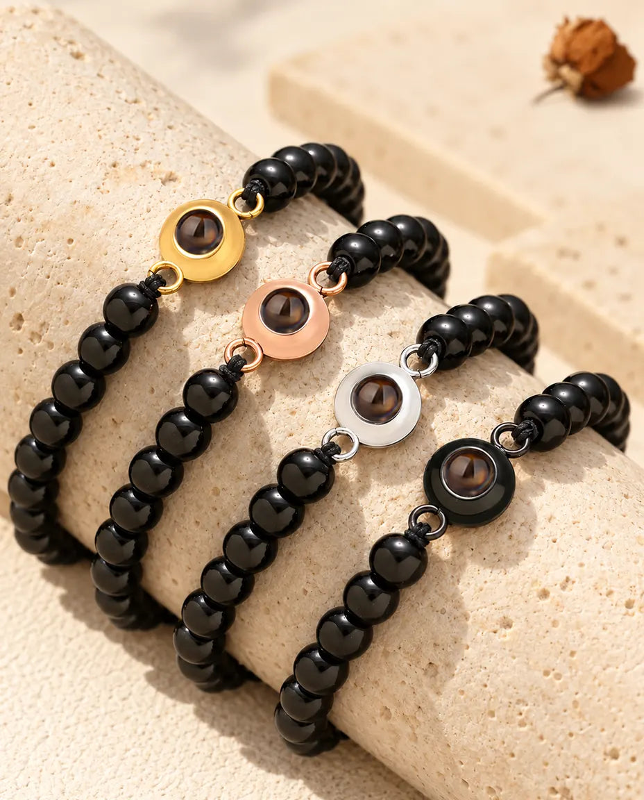 Pulseras de bolas negro brillante en los cuatro colores de aro sobre un bloque de travertino