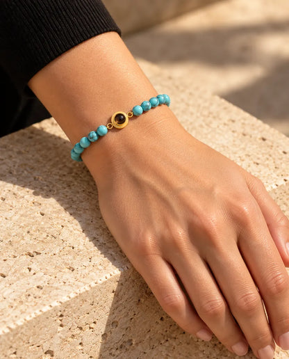 Mujer con la pulsera de bolas azul jaspeado y su aro dorado de proyección en la muñeca