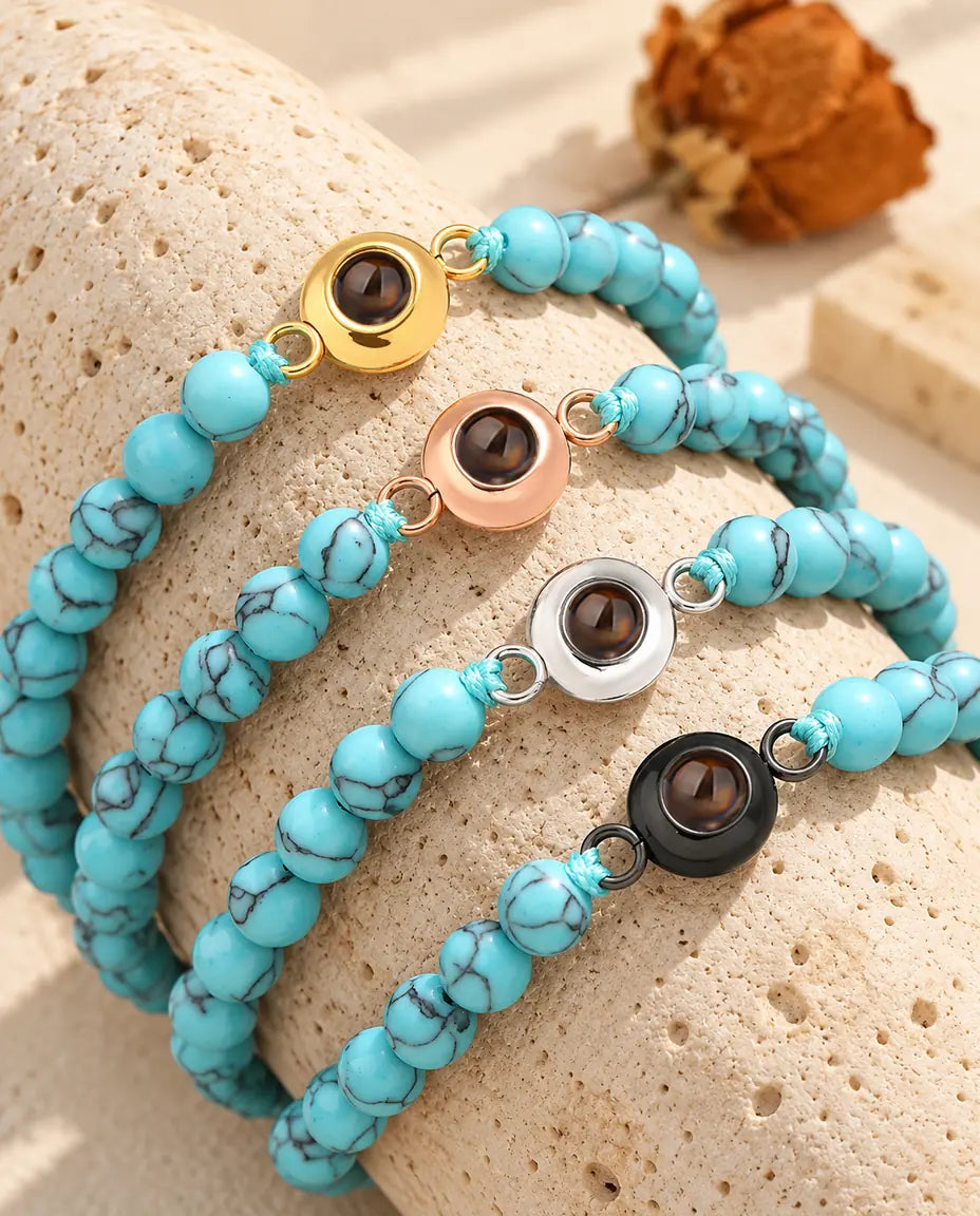Cuatro pulseras de bolas azul jaspeado con aro dorado, color oro rosa, plateado y negro sobre travertino