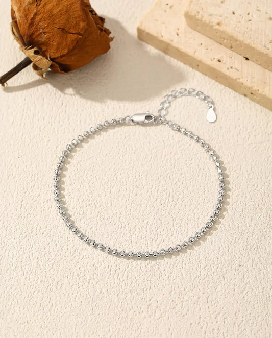Pulsera de Bolitas Facetadas en Plata 925 - extendida sobre una superficie clara con textura, con cierre y alargador