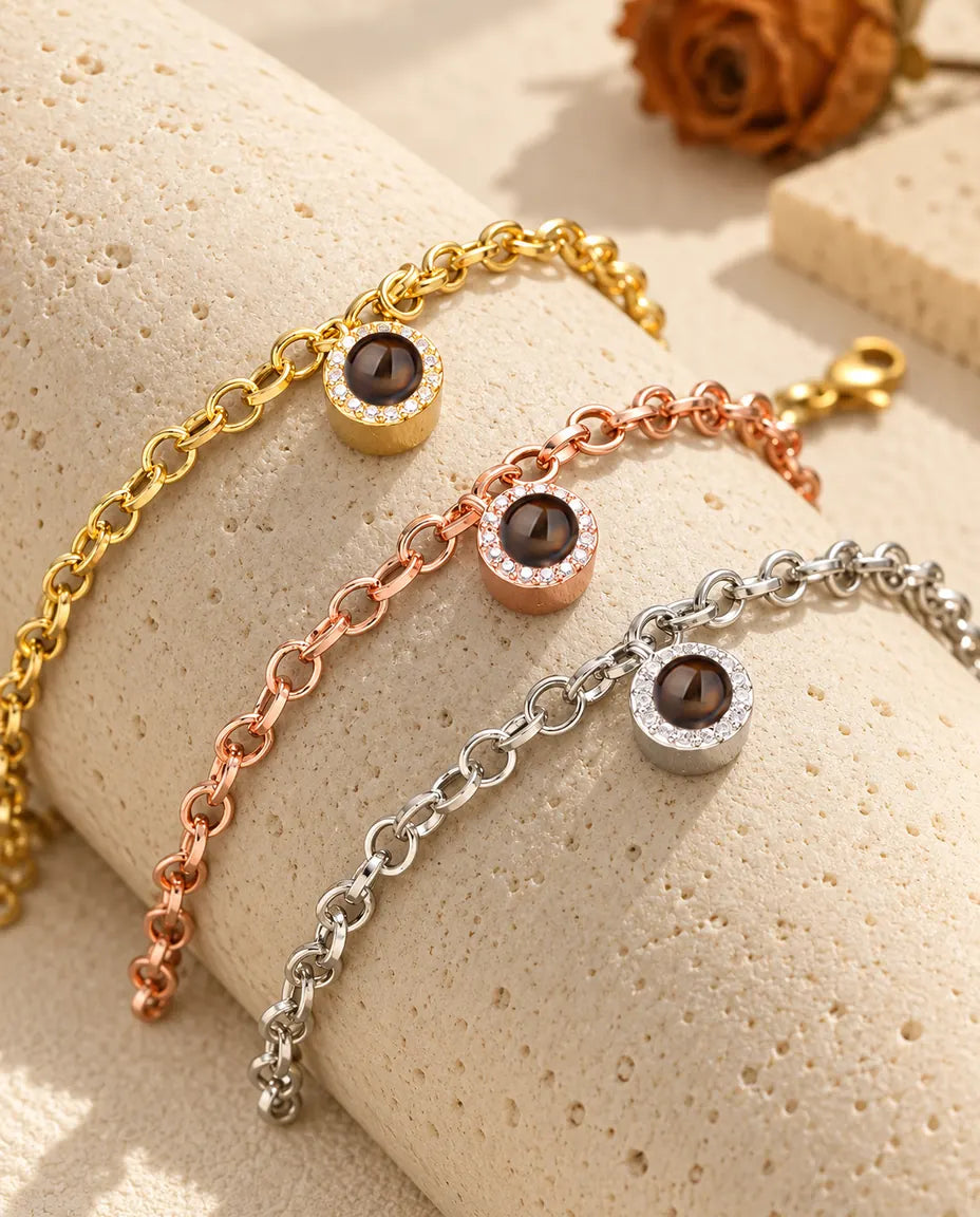 Pulseras con colgante redondo de circonitas en dorado, color oro rosa y plateado sobre un bloque de travertino