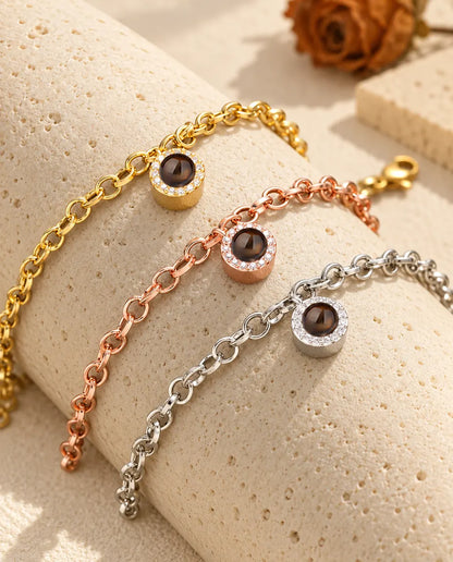 Pulseras con colgante redondo de circonitas en dorado, color oro rosa y plateado sobre un bloque de travertino