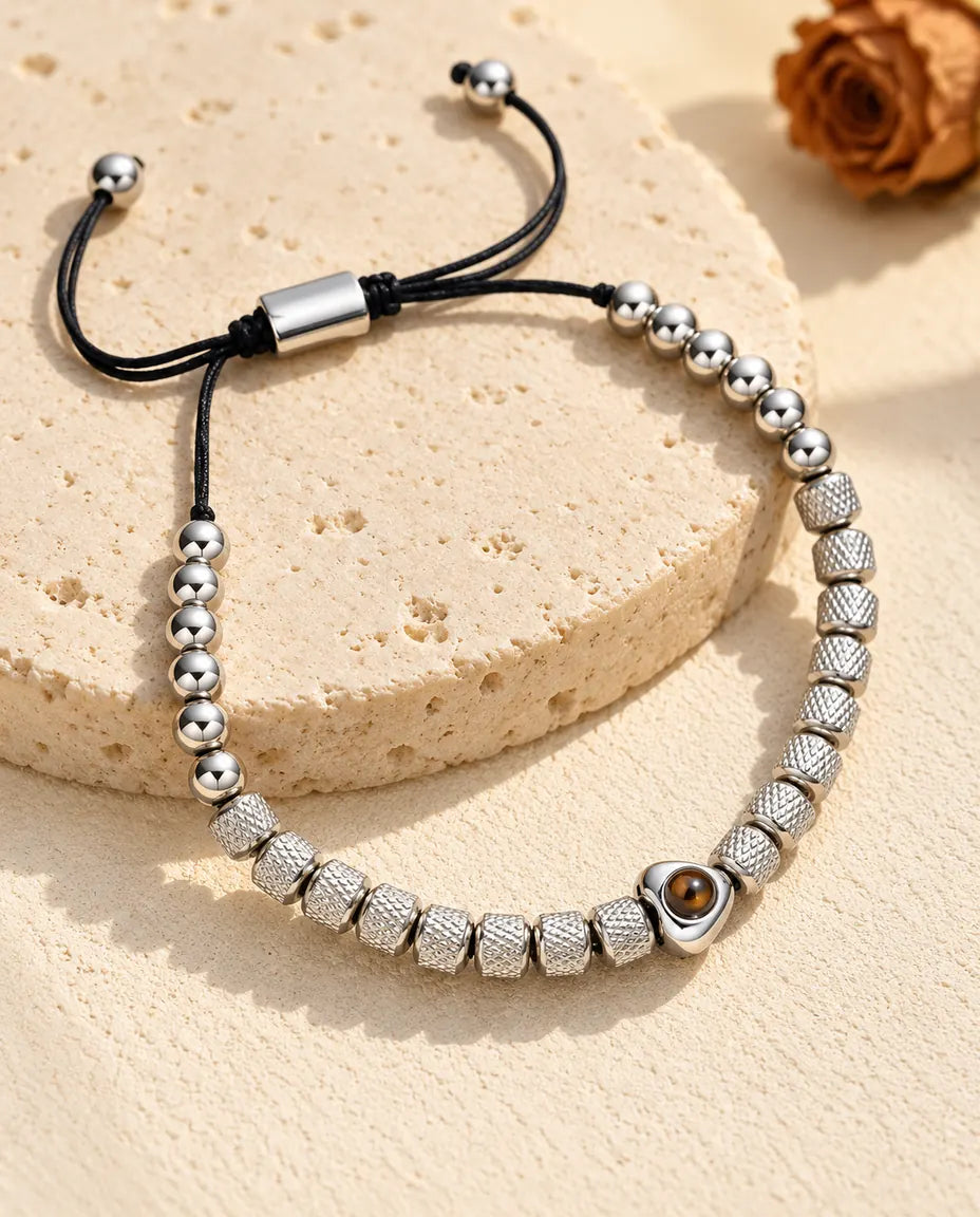 Pulsera de cuentas con foto dentro personalizada en plateado, con corazón y cuentas texturadas, sobre travertino