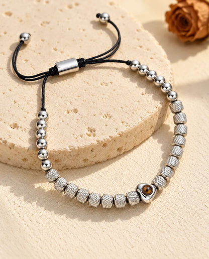 Pulsera de cuentas con foto dentro personalizada en plateado, con corazón y cuentas texturadas, sobre travertino