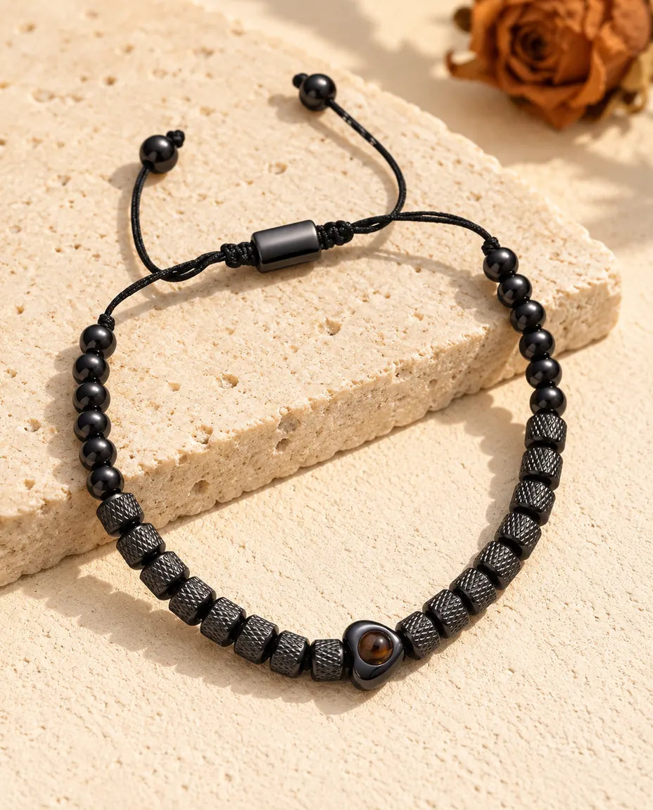 Pulsera negra de cuentas texturadas con corazón, pasador deslizante y bolitas en los extremos del cordón