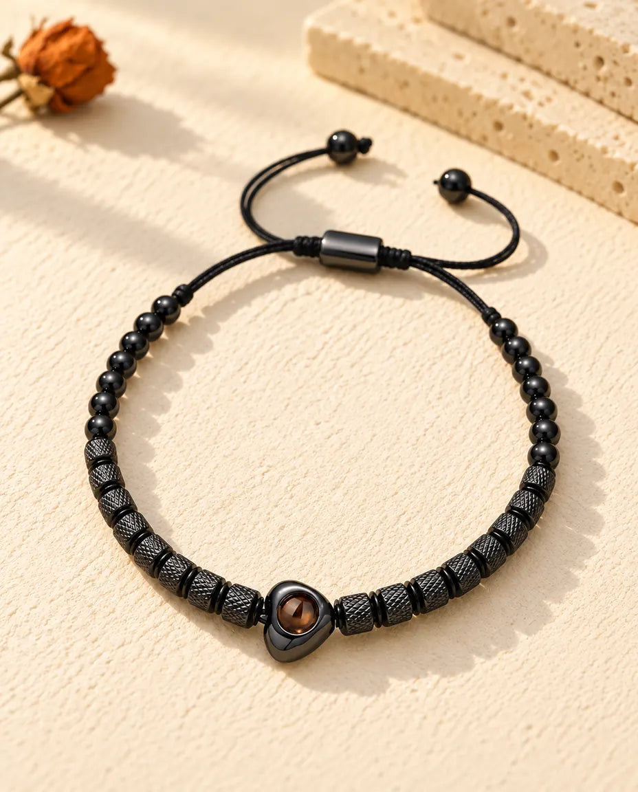 Vista cenital de la pulsera negra de cuentas con corazón y foto dentro sobre yeso crema