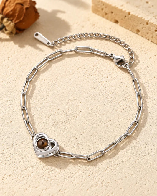 Pulsera con foto dentro personalizada, plateada, con doble corazón en cadena de eslabones clip, sobre yeso color crema