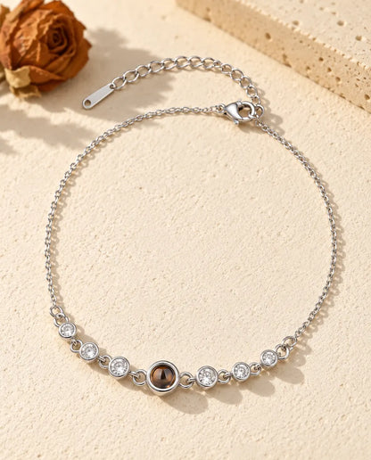 Pulsera con foto dentro personalizada en plateado con una fila de circonitas en cadena fina, sobre yeso crema