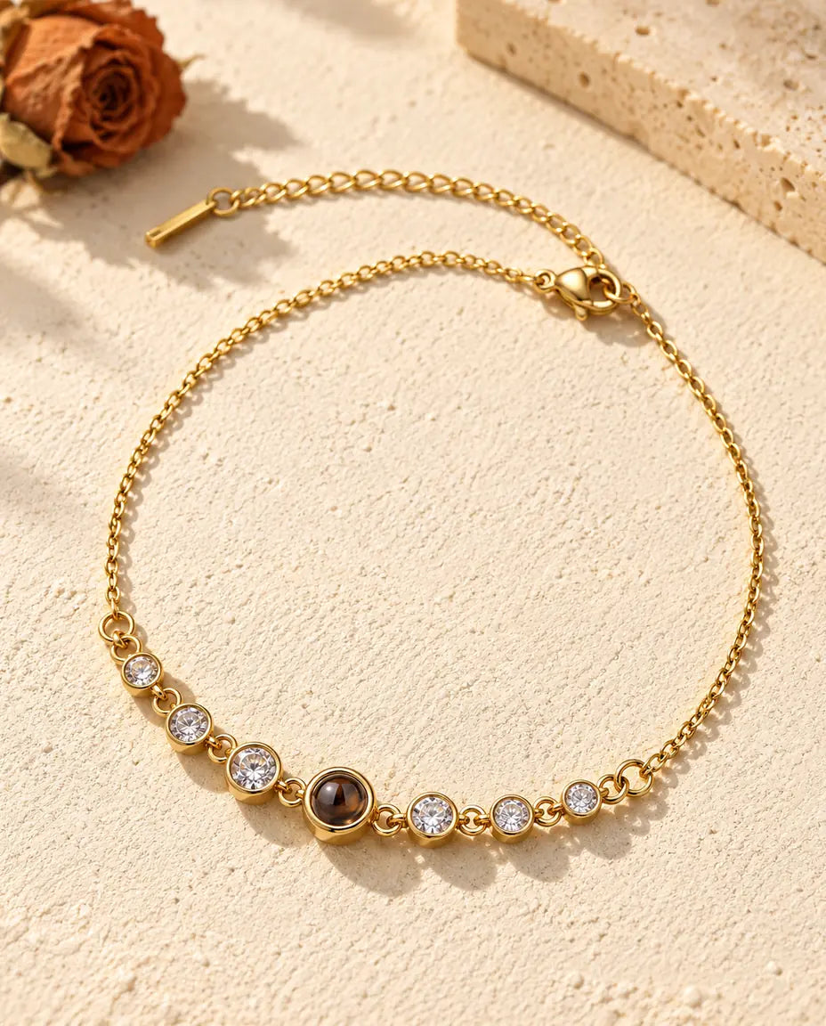 Pulsera de acero inoxidable dorada con circonitas y una pequeña piedra marrón en el centro