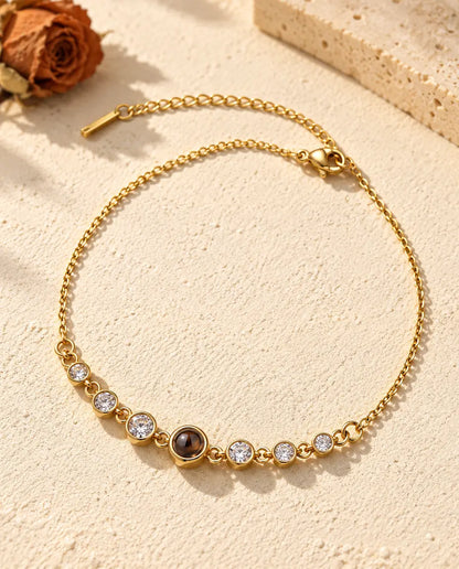 Pulsera de acero inoxidable dorada con circonitas y una pequeña piedra marrón en el centro