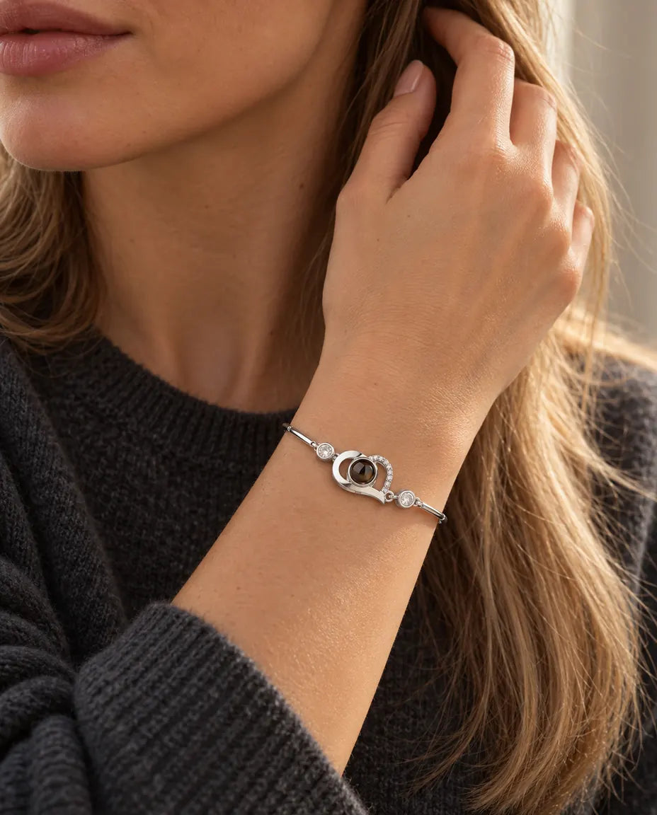 Mujer con la mano en el pelo y la pulsera plateada de corazón abierto con foto dentro