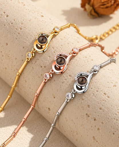 Tres pulseras de corazón abierto en dorado, color oro rosa y plateado sobre un bloque de travertino