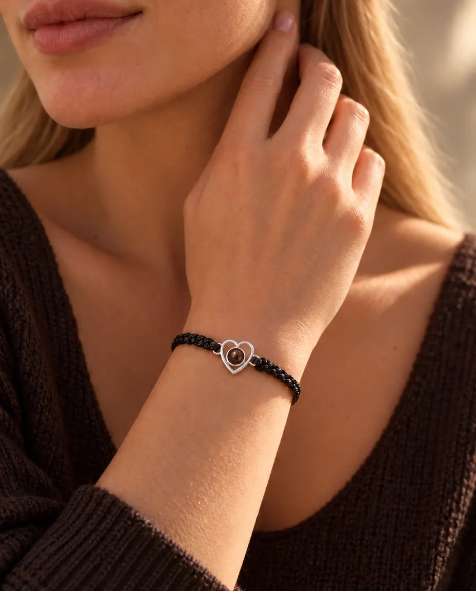 Mujer con las yemas de los dedos en el lateral del cuello, con la pulsera de corazón abierto de plata y cordón negro