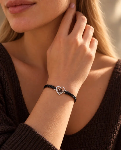 Mujer con las yemas de los dedos en el lateral del cuello, con la pulsera de corazón abierto de plata y cordón negro