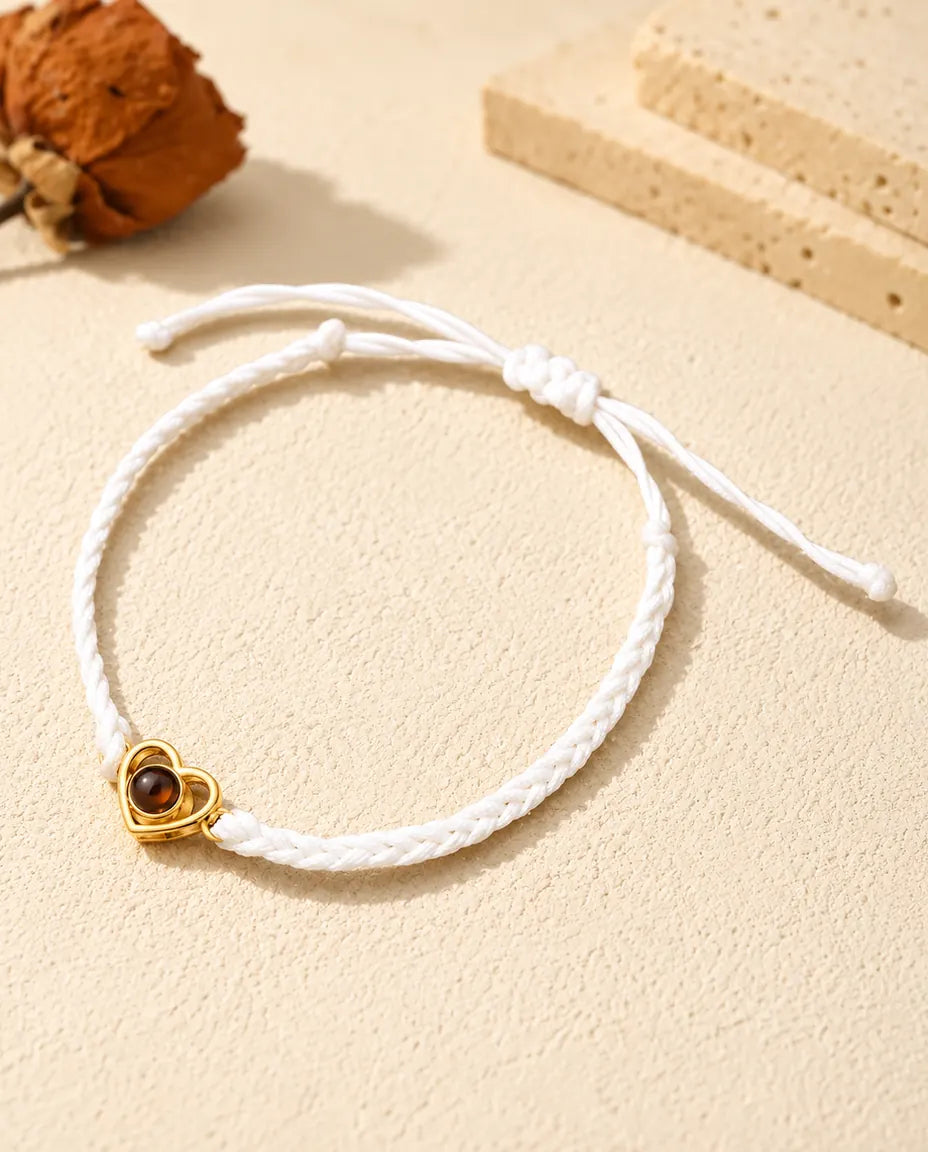 Pulsera con foto dentro de cordón trenzado blanco, con corazón abierto dorado y nudo corredizo