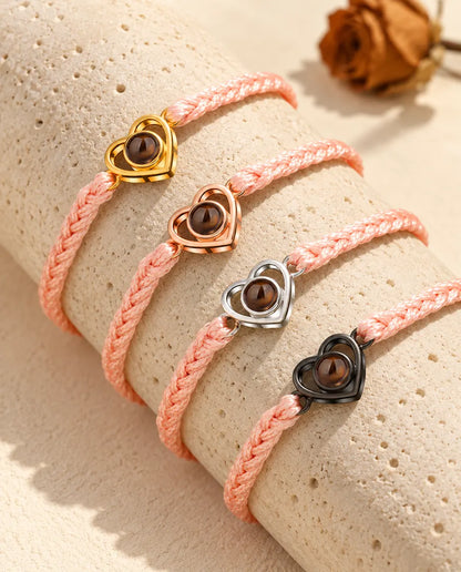 Pulseras de cordón trenzado rosa con el corazón abierto en todos sus colores, sobre travertino