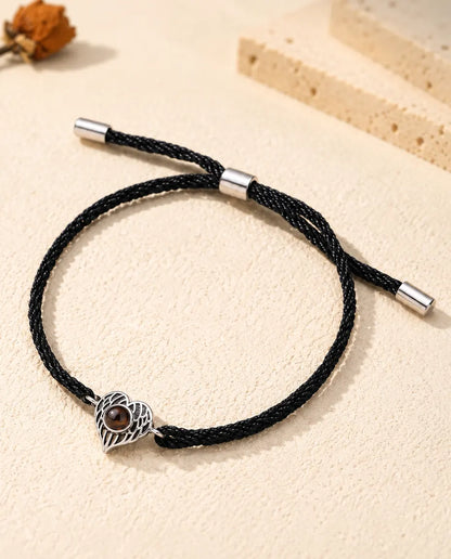 Pulsera con foto dentro personalizada: corazón de alas de ángel plateado en cordón negro torcido, sobre yeso crema