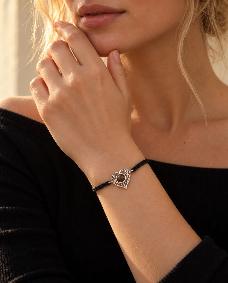 Mujer con las yemas de los dedos en la mandíbula, con la pulsera de corazón de alas de ángel plateado