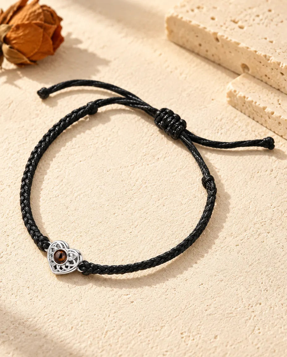 Pulsera con foto dentro personalizada: corazón calado plateado en cordón trenzado fino negro, sobre yeso color crema