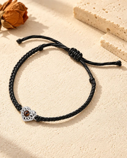 Pulsera con foto dentro personalizada: corazón calado plateado en cordón trenzado fino negro, sobre yeso color crema