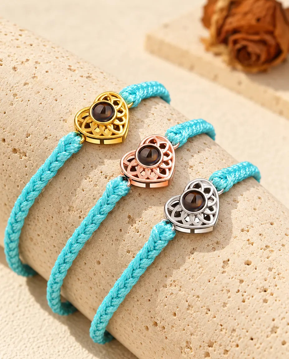 Pulseras de cordón trenzado fino azul con corazón dorado, color oro rosa y plateado sobre travertino