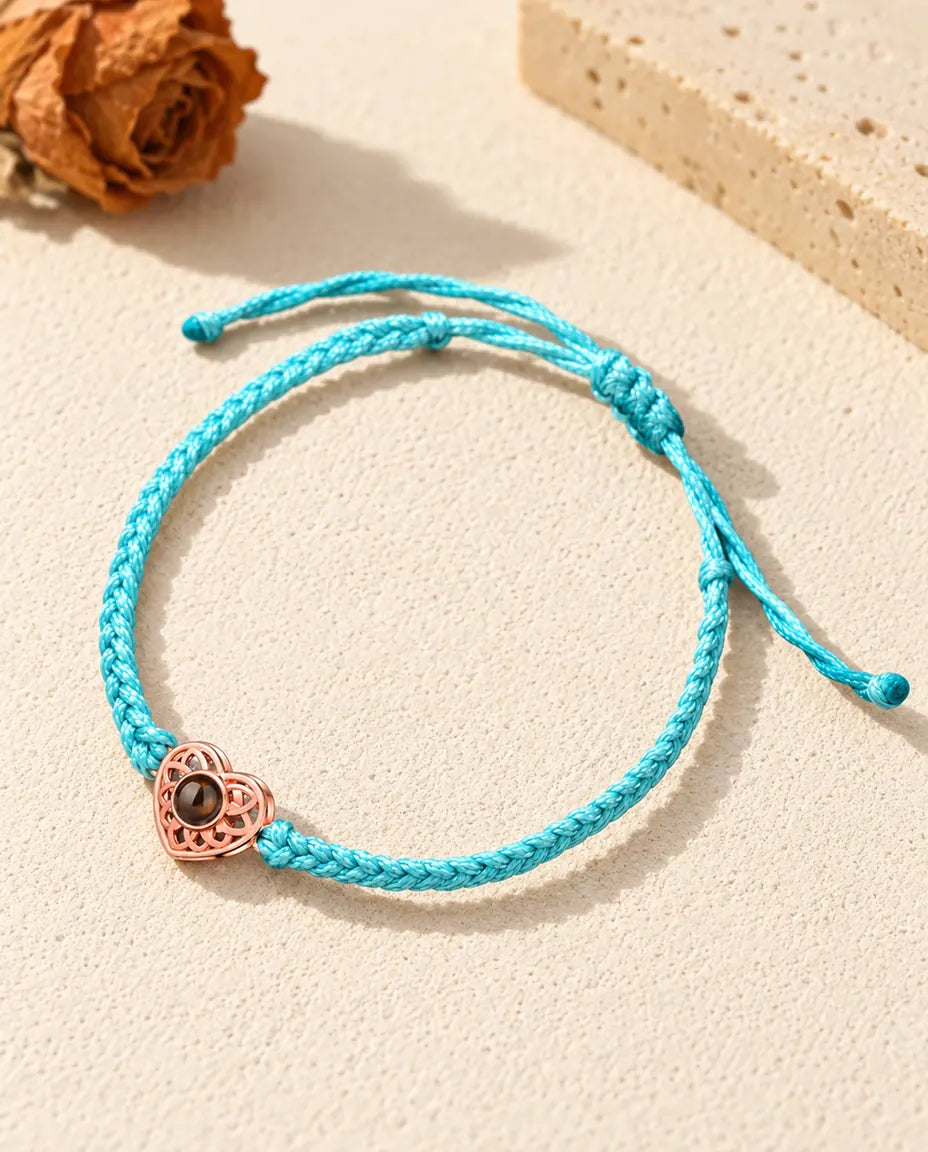 Corazón color oro rosa en un cordón trenzado fino azul con nudo corredizo ajustable