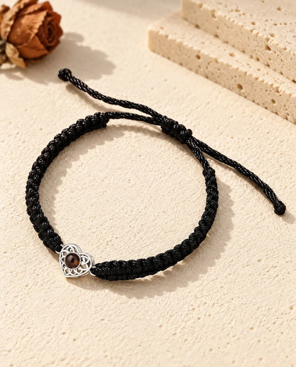 Pulsera con foto dentro personalizada: corazón calado plateado en cordón trenzado negro, sobre yeso color crema