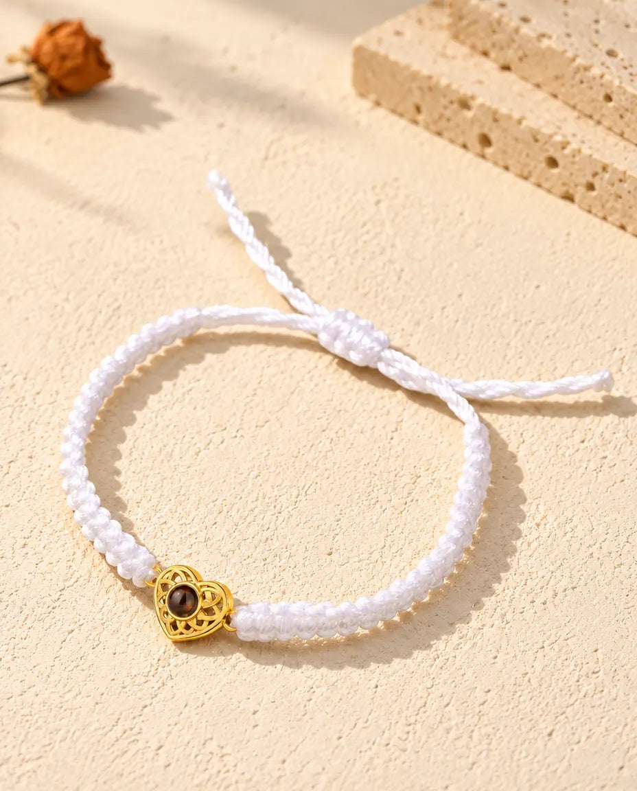 Pulsera con foto dentro de cordón trenzado blanco, con corazón dorado y cierre de nudo corredizo
