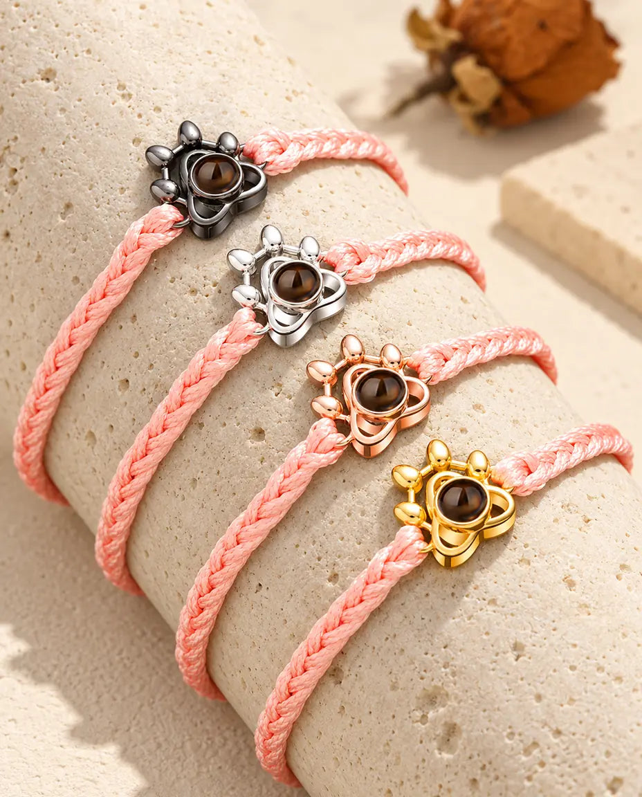 Pulseras de cordón trenzado rosa con la huella en todos sus colores, colocadas sobre travertino