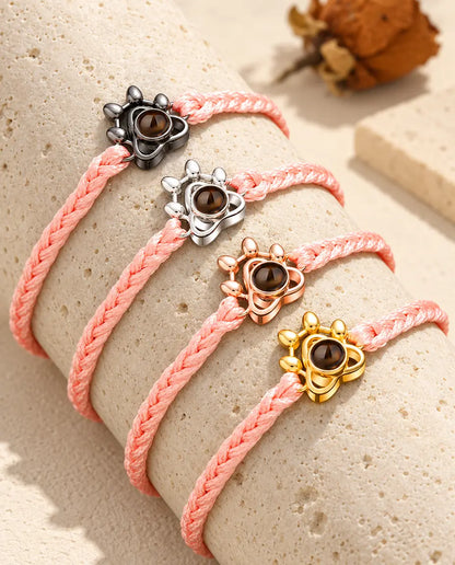 Pulseras de cordón trenzado rosa con la huella en todos sus colores, colocadas sobre travertino
