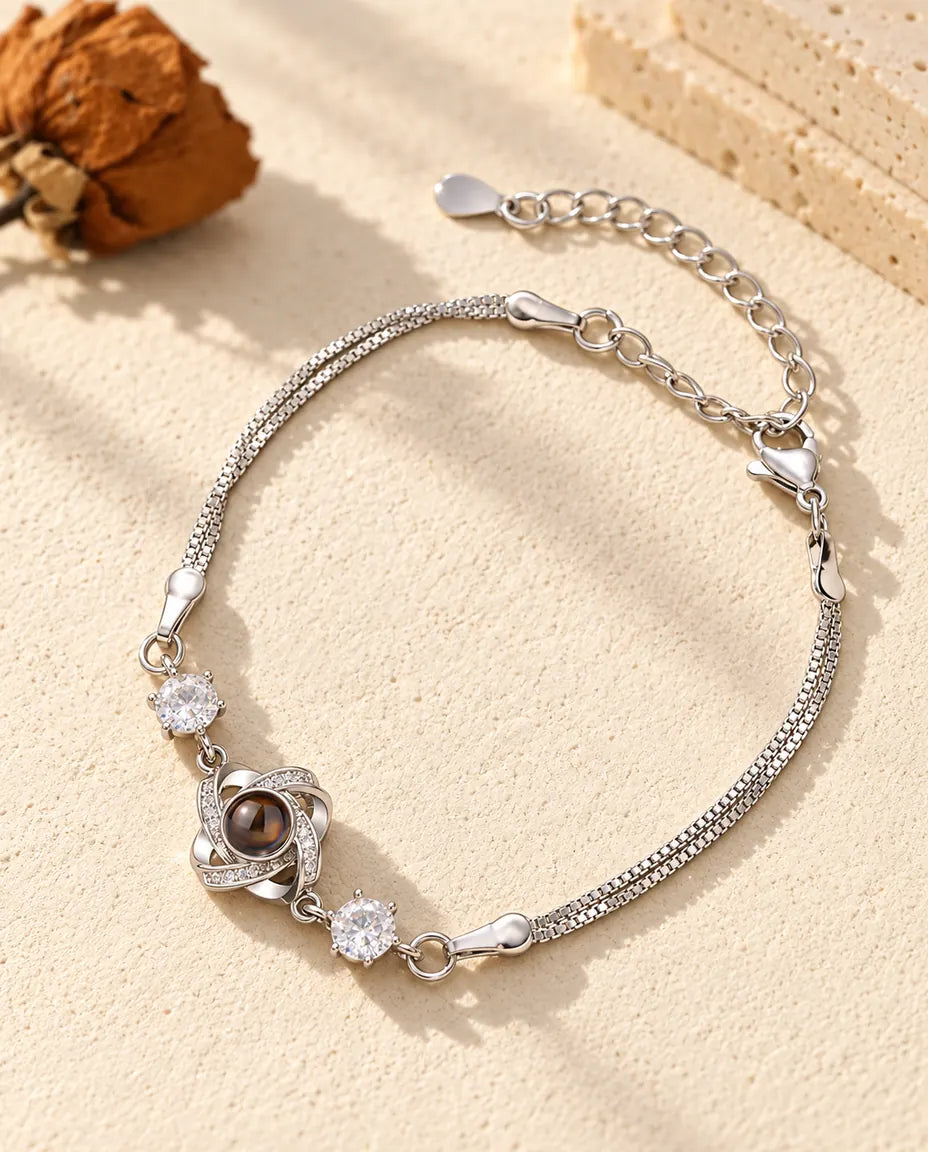 Pulsera con foto dentro personalizada en plateado con nudo de amor y dos circonitas en doble cadena, sobre yeso crema