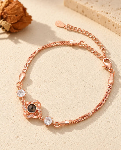 Pulsera de nudo de amor color oro rosa con circonitas brillantes a los lados y doble cadena veneciana