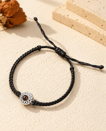 Pulsera con foto dentro personalizada: círculo calado plateado en cordón trenzado fino negro, sobre yeso color crema