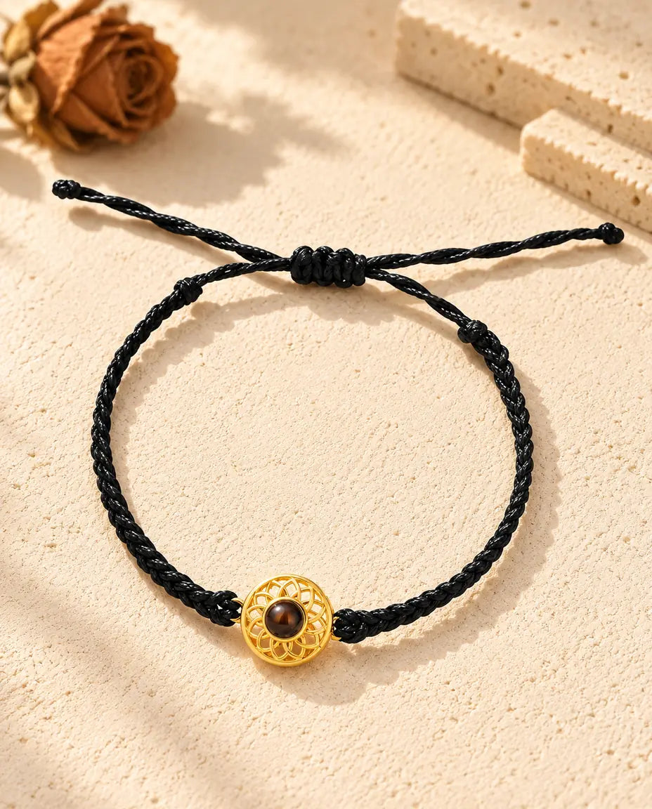 Vista cenital de la pulsera de círculo dorado en cordón trenzado fino negro, con el nudo corredizo y sus extremos