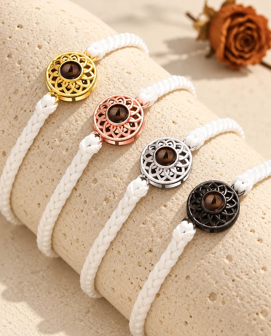 Cuatro pulseras de cordón fino blanco con círculo dorado, color oro rosa, plateado y negro sobre travertino