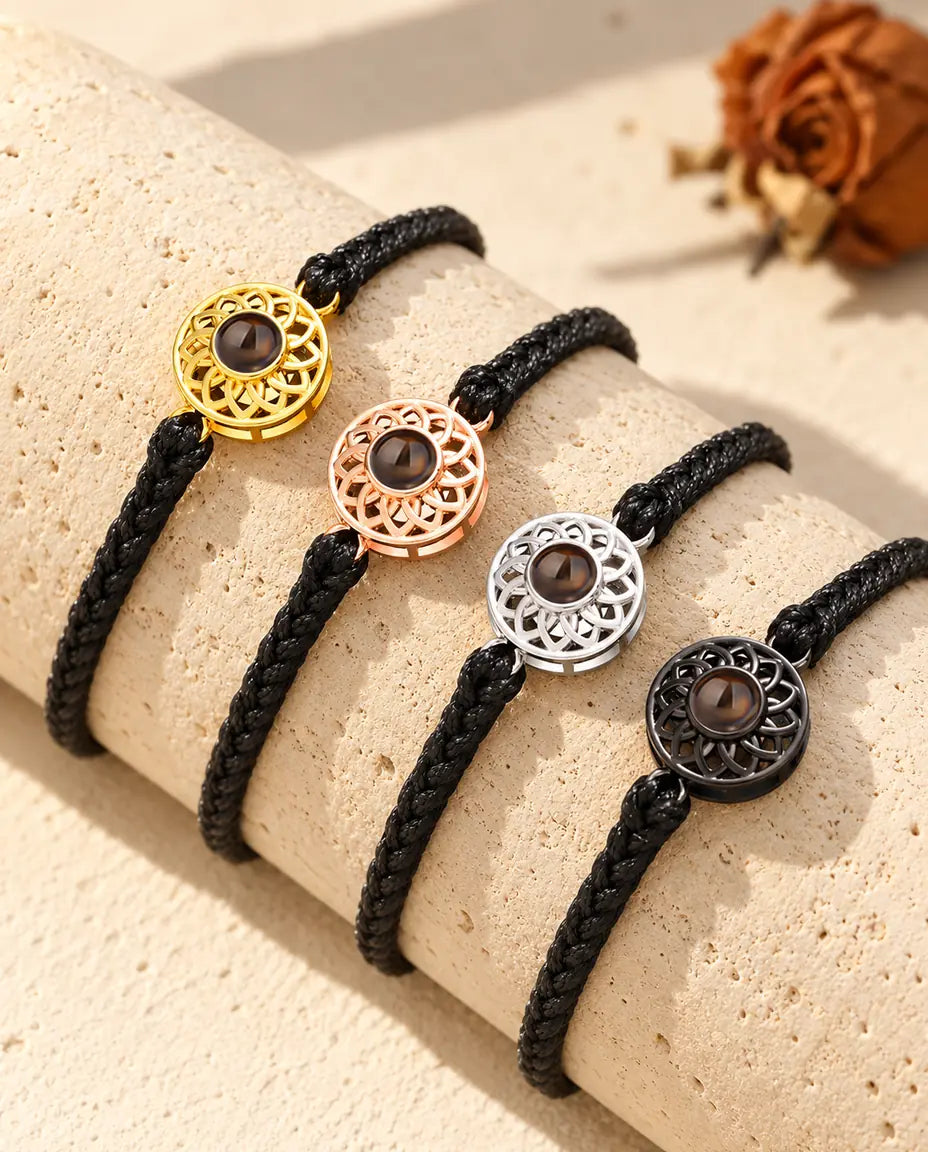 Cuatro pulseras de cordón trenzado fino negro con todos los colores de círculo, colocadas sobre travertino